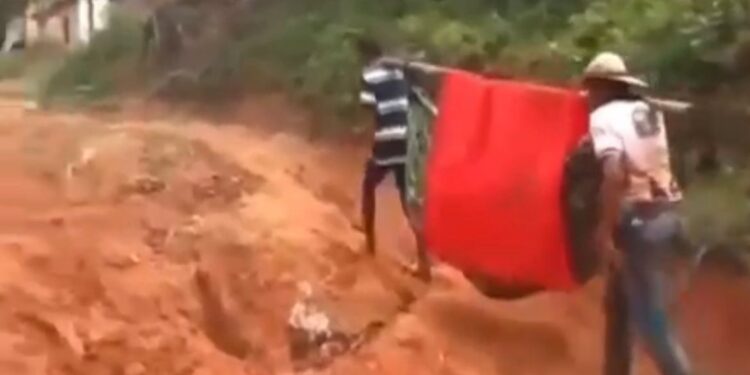 Moradores carregam uma pessoa doente em rede por falta de ambulância