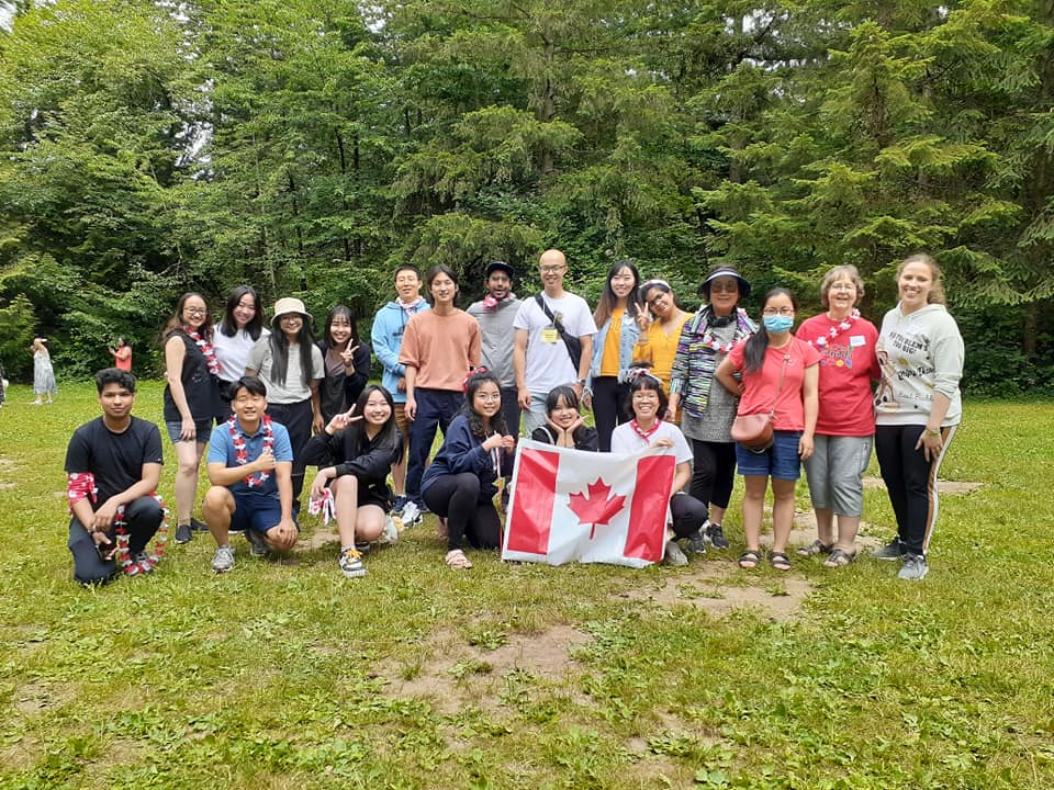 Diverse group holding a Canadian flag outdoors