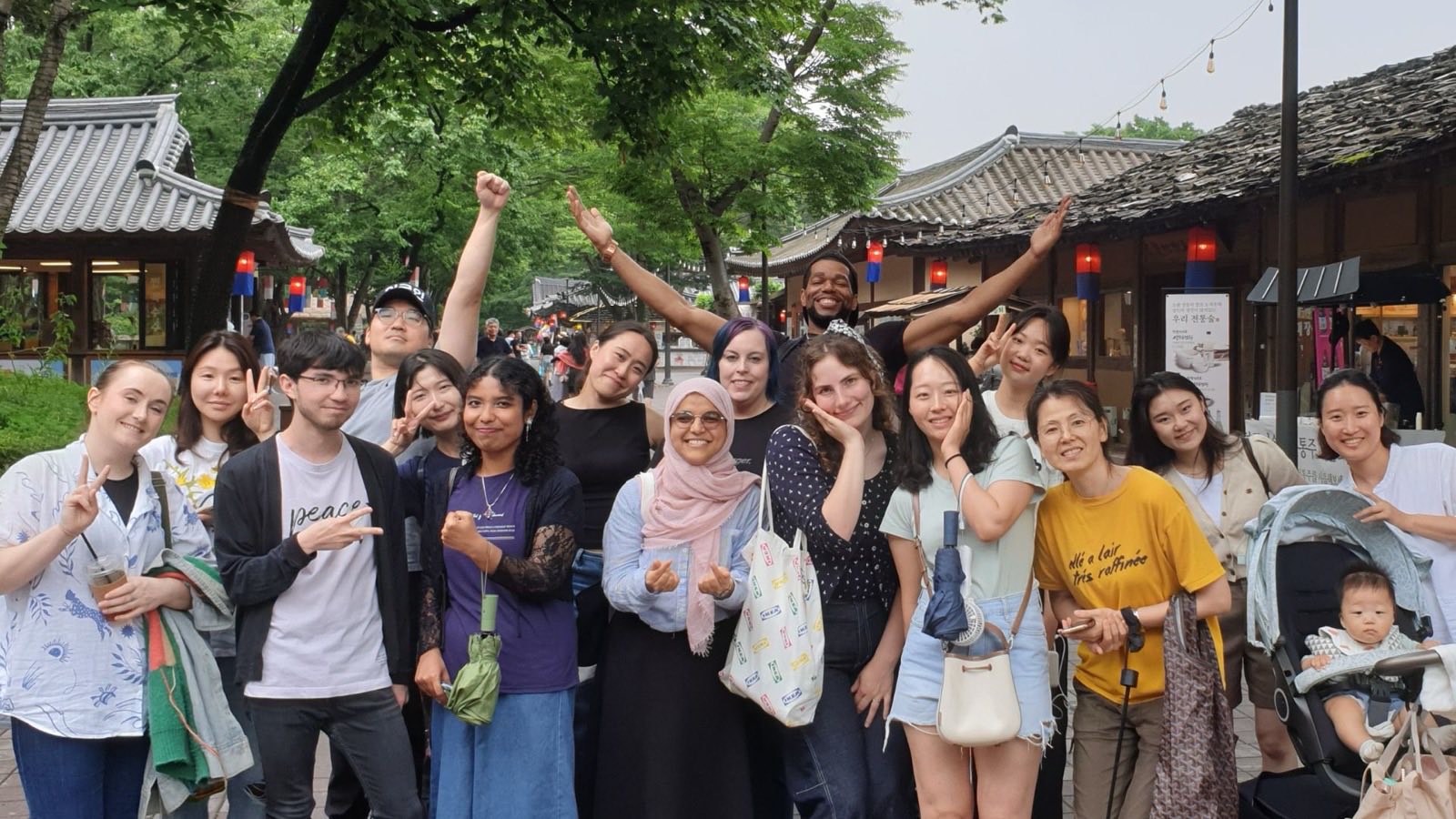 Diverse group posing on a street with traditional Korean buildings