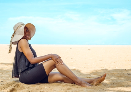 Femme assise dans du sable en bordure de plage