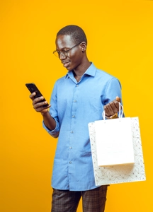 Bel homme avec des lunettes regardant sur son téléphone avec des sacs de shopping