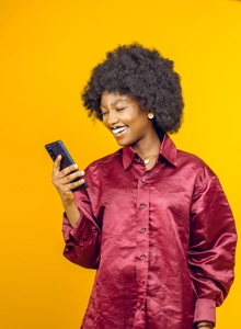 Belle femme afro avec un grand sourire regardant dans son téléphone