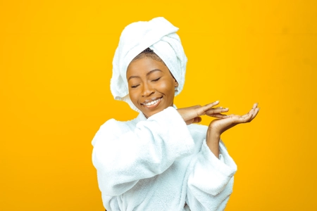 belle femme en peignoir blanc faisant ses  soins du  corps avec délicatesse