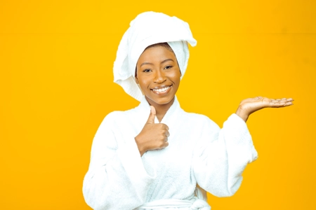 belle femme en peignoir blanc montrant un produit de beauté  avec sourire