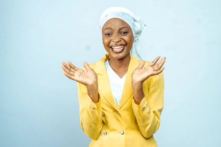 Belle femme souriante avec un veste jaune, un foulard avec les deux mains en l'air