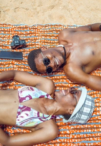 couple couché sur un pagne dans le sable avec joie