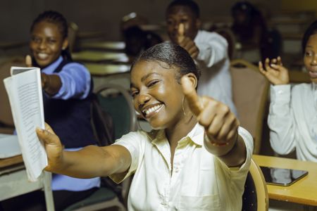 Des étudiants heureux en classe avec le pousse levé