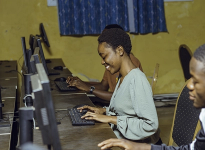 Des étudiants souriant entrain de travailler sur leur machine dans la salle d'informatique