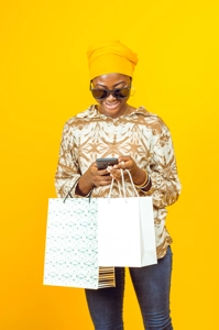 Femme avec des lunettes de soleil, un téléphone et des sacs de shopping