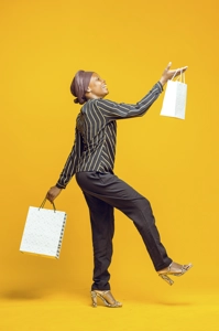 Femme avec deux sacs de shopping et un pied en l'air