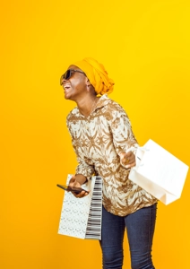 Femme avec éclat de rire, un téléphone et des sacs de shoppings