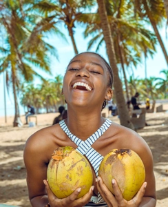 femme en joie tenant des noix de coco à la plage
