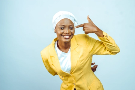 Femme souriante avec un doigt pointé sur sa tête et un foulard