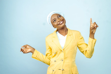 Femme souriante en veste et un foulard pointe les doigts en l'air