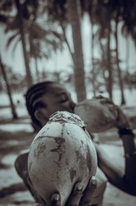 femme tenant des noix de coco entre des cocotiers