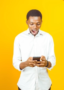 homme étonné ouvrant grandement la bouche en regardant sur son téléphone