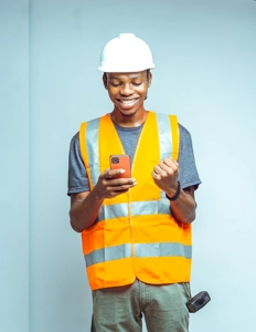 ingénieur bâtiment portant un gilet et un casque manipulant un téléphone