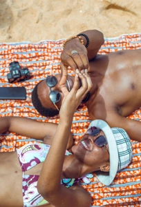 jeune couple couché dans le sable faisant un cœur avec les mains jointes