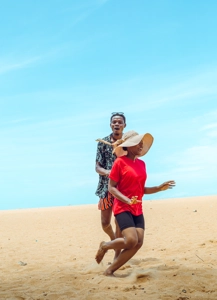 jeune homme homme courant derrière une femme portant un chapeau sur la plage