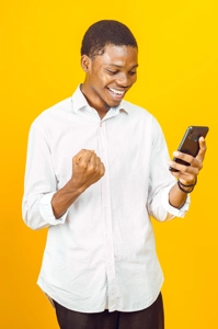 jeune homme sautant de joie en regardant sur téléphone