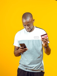 Jeune homme souriant sur son téléphone et une carte de crédit