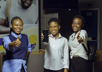 Trois étudiantes souriantes le pouce levé dans le hall