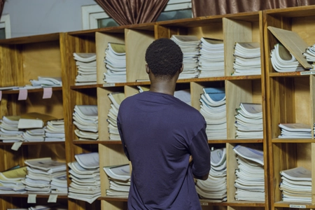 Un étudiant devant les étagères du bibliothèque entrain de réfléchir