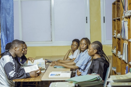 Un groupe d'étudiant assis dans la bibliothèque autour d'une table entrain de discuter