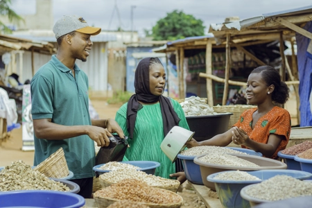 Une commerçante de céréale et ses clients devant sa marchandise au marché