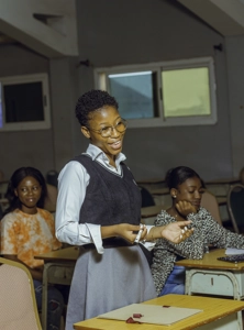 Une étudiante avec des lunettes debout en classe en train de parler