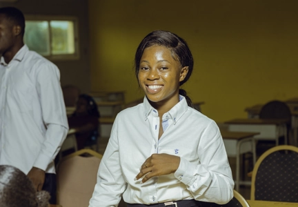 Une étudiante debout souriante en classe