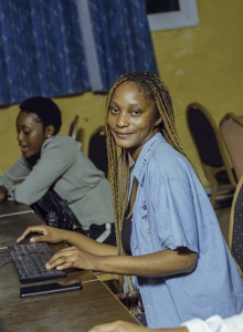 Une étudiante en salle d'informatique devant son ordinateur les doigts sur le clavier