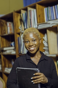 Une étudiante souriante avec un cahier dans la bibliothèque