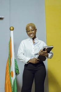 Une étudiante souriante en uniforme tenant un cahier