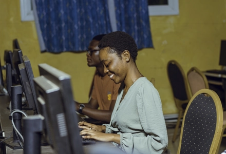 Une jeune fille en souriant en salle d'informatique avec un ordinateur