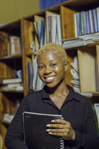 Une jeune fille étudiante souriante avec des documents dans une bibliothèque