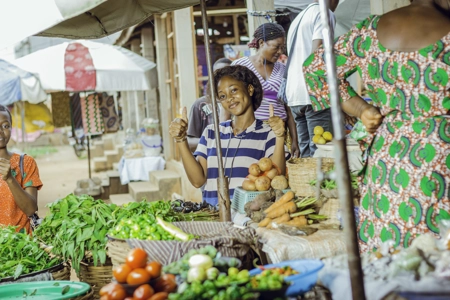 Une jeune fille heureuse près de la marchandise de légumes