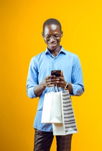 Une jeune homme avec son téléphone des deux sacs de shopping