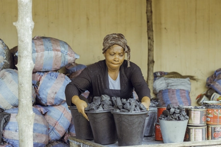 Une vendeuse de charbon devant sa marchandise