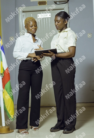 Deux étudiantes en uniforme dans le hall tenant une tablette