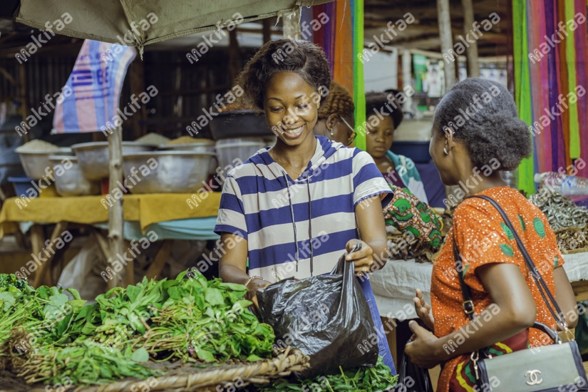 La vendeuse entrain de vendre des légumes d'adémè à une cliente