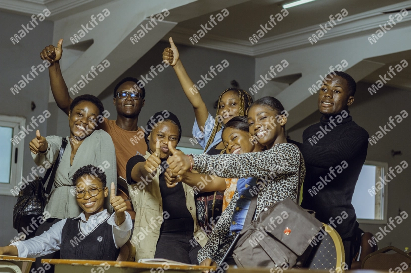 Un groupe d'étudiants souriant dans la classe le pouce levé