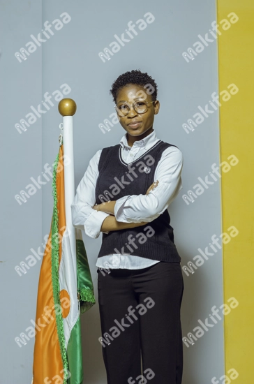 Une étudiante en uniforme les bras croisés se tient près d'un drapeau