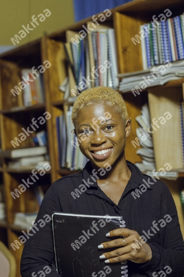 Une étudiante souriante avec un cahier dans la bibliothèque