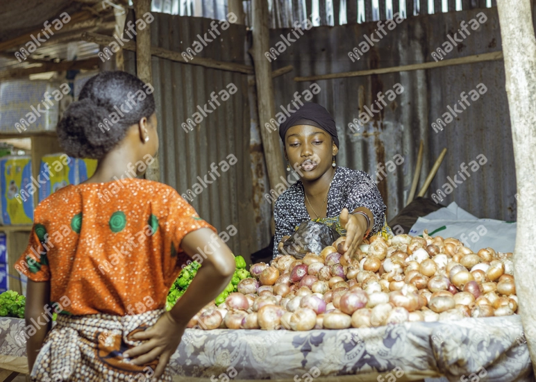 Une femme entrain de vendre des oignons et piments