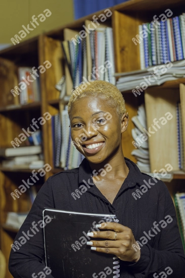 Une jeune fille étudiante souriante avec des documents dans une bibliothèque