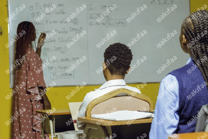 Une professeure au tableau expliquant le cours aux étudiants