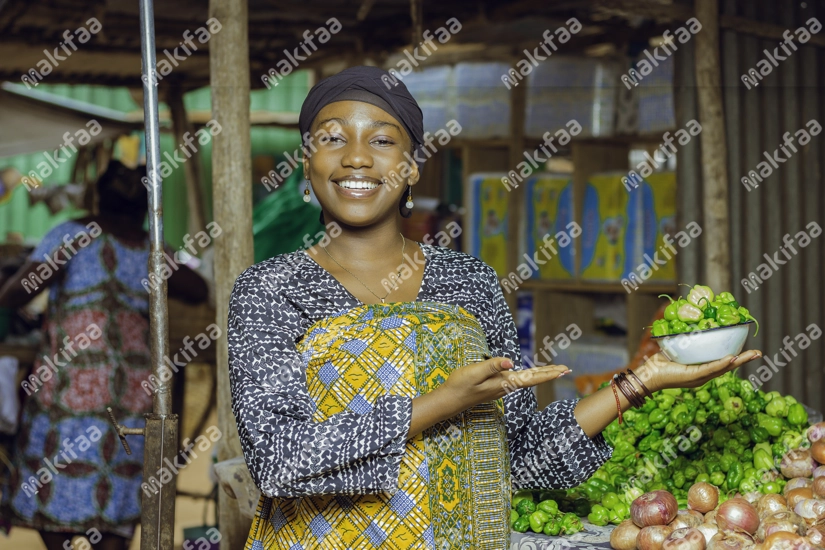 Une revendeuse souriante montrant un bol de piment vert