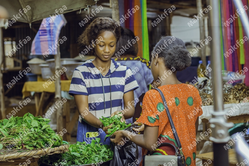 Une commerçante vendant des légumes d'adémè dans un sachet à sa cliente