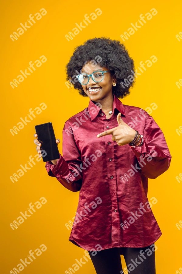 Belle femme afro portant des lunettes montre son téléphone du doigt